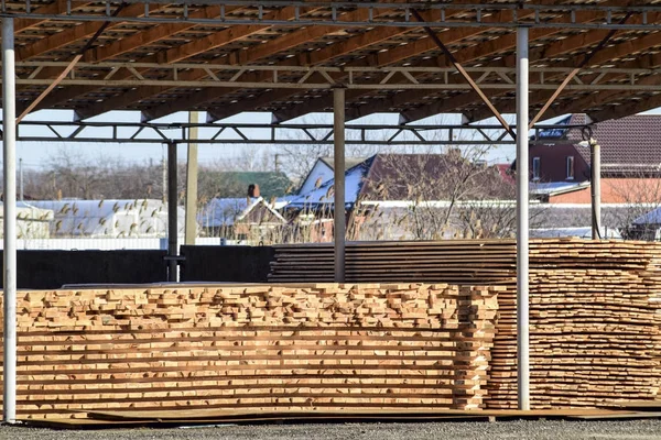 Warehouse of building materials, wood planks stacked under a canopy