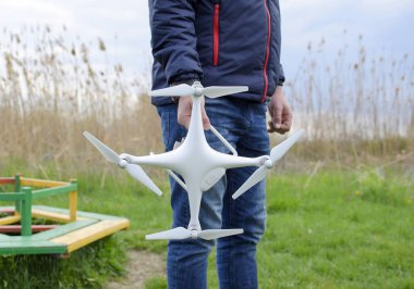 Quadrocopter onun elinde olan bir adam. Beyaz bir drone uçuş için hazırlanıyor. Hayalet
