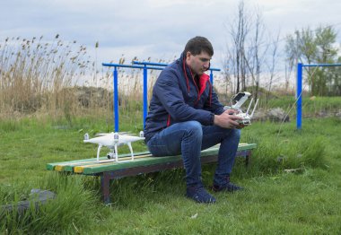 Uzaktan kumanda quadroopter onun elinde olan bir adam oturuyor 