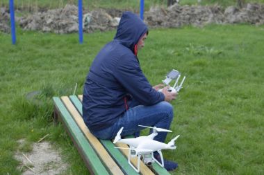 Uzaktan kumanda quadroopter onun elinde olan bir adam oturuyor 