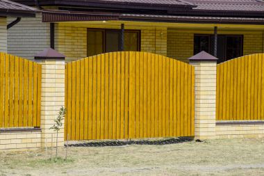 Oluklu metal profil çatısı ve ahşap çit tuğla ev. Güzel manzara cephe. Stil tasarım.