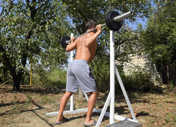 Mann nimmt Bar, um Kniebeugen durchzuführen. Übungen im Bodybuilding. sp — Stockfoto