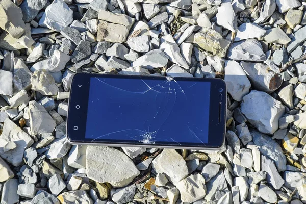 Frustrated phone on the rocks. Glass shattered on rocks on a sma