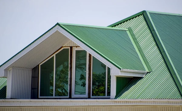 The house with plastic windows and a green roof of corrugated sh — Stock Photo, Image