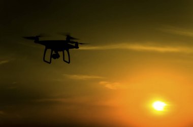 Quadrocopters siluet güneşin arka planı. Akşam gökyüzünde uçan uçaklar.