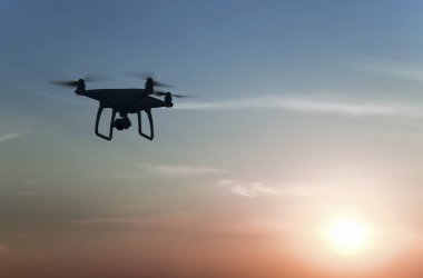 Quadrocopters siluet güneşin arka planı. Akşam gökyüzünde uçan uçaklar.