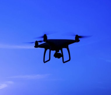 Quadrocopters siluet güneşin arka planı. Akşam gökyüzünde uçan uçaklar.