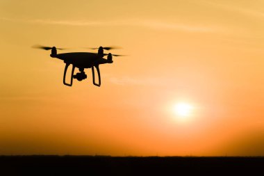 Quadrocopters siluet güneşin arka planı. Akşam gökyüzünde uçan uçaklar.