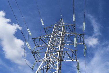 Yüksek voltajlı elektrik hatları clou ile mavi gökyüzüne karşı destekler