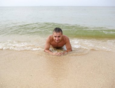 adam sahilde yatıyor. Dalga deniz eril kapsar. Beach 