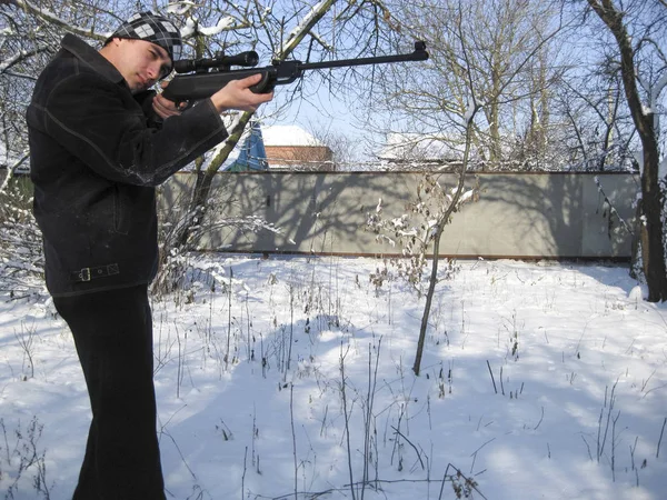 Uomo con un fucile ad aria compressa in un parco invernale . — Foto Stock