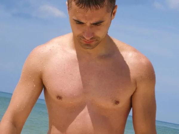 Mužské torzo. Svalnatý mladý muž stojí na pláži. — Stock fotografie