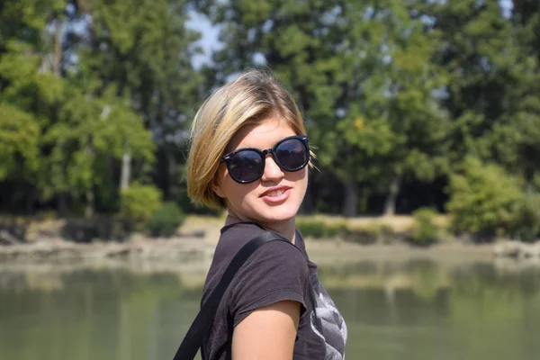 Genç güzel kız nehir manzara, portre sarışın arka planı güneş gözlüğü