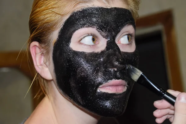 Дівчина в косметичній чорній масці. Маска для очищення аспірину та активованого вугілля. Чорна косметична маска для обличчя . — стокове фото