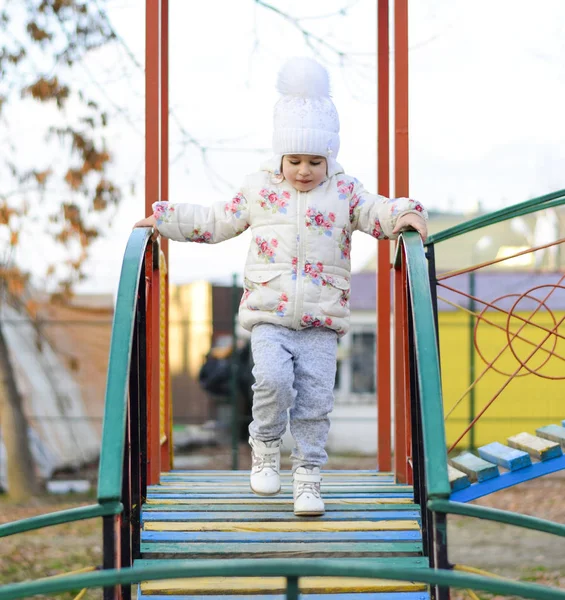 Dziewczynka bawi się na placu zabaw w parku. Dziecko idzie na schodach plac zabaw. — Zdjęcie stockowe