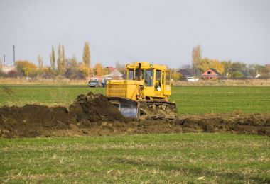 Sarı traktör ekli grederom ile zemin tesviye yapar. Drenaj sistemi alanında çalışmak.