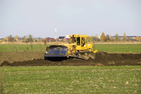 Grederom と黄色のトラクターは 地面の平準化します フィールドにおける排水を作業します — ストック写真