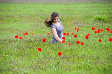 Güzel peri kız lale çiçekleri arasında bir alanda. Kırmızı çiçekler ve yeşil bir alana bir arka plan üzerinde bir kız portresi. Lale alan.