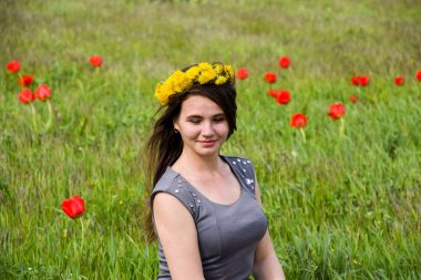 Güzel peri kız lale çiçekleri arasında bir alanda. Kırmızı çiçekler ve yeşil bir alana bir arka plan üzerinde bir kız portresi. Lale alan.