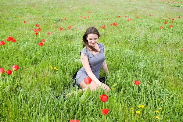 Güzel peri genç kız lale çiçekleri arasında bir alanda — Stok fotoğraf