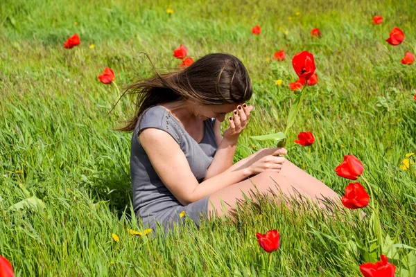 Güzel peri kız lale çiçekleri arasında bir alanda. Kırmızı çiçekler ve yeşil bir alana bir arka plan üzerinde bir kız portresi. Lale alan.
