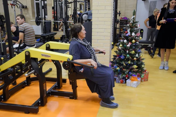 Une femme âgée est engagée dans la salle de gym sur le simulateur . — Photo