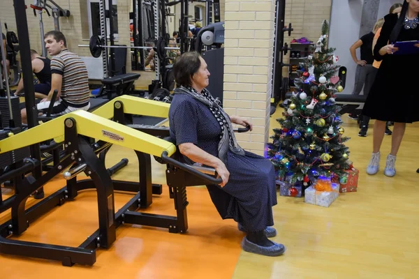 Une femme âgée est engagée dans la salle de gym sur le simulateur . — Photo
