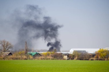 Yangın ve siyah duman köyün dışında. Yanan kurum