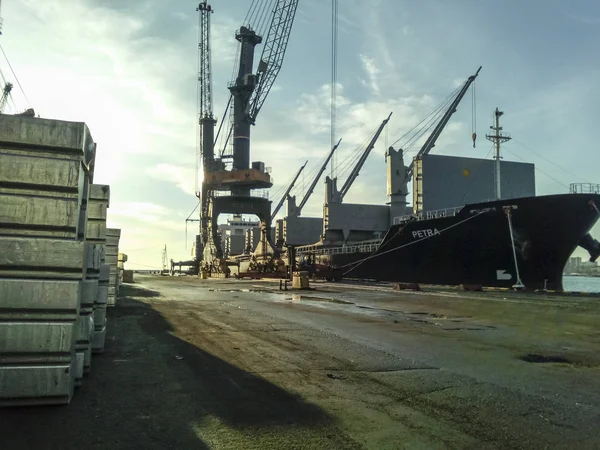 De metalen staven gevouwen op de site van de poort voor export. Tijdelijke opslag in de haven van grondstoffen. Lading van de haven en kranen. — Stockfoto