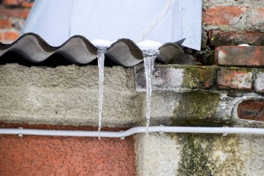 Buz sarkıtları çatıda. Güvensiz çatı. Icicle dondurucu suda.