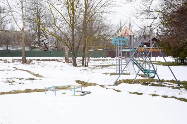 Barnens lekplats på vintern under snön. Swing, karusell och vattenrutschbana. Vinter desolation — Stockfoto