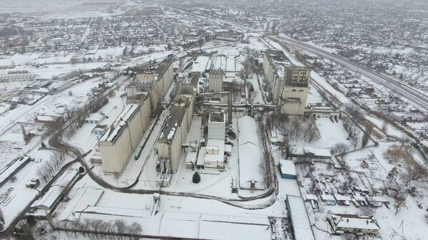 Grain terminal in the winter season. Snow-covered grain elevator in rural areas. A building for drying and storing grain