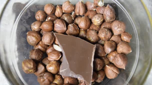 Mjölkchoklad och hasselnötter i en glas-kopp. — Stockvideo