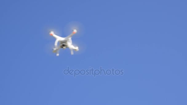 Дрон DJI Phantom 4 в полете. Квадровертолет против голубого неба с белыми облаками. Полет вертолёта в небе . — стоковое видео