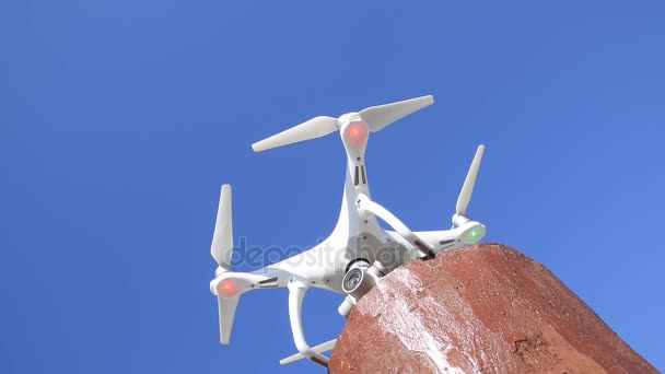 Drone DJI Phantom 4. Le drone coûte sur un support rouge et se prépare au décollage. Le drone sur fond blanc . — Video