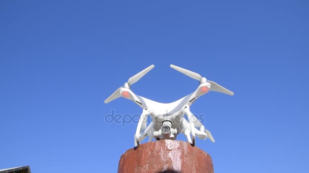 Drone DJI Phantom 4. The drone costs on a red support and prepares for take-off. The drone on a white background. — Stock Video