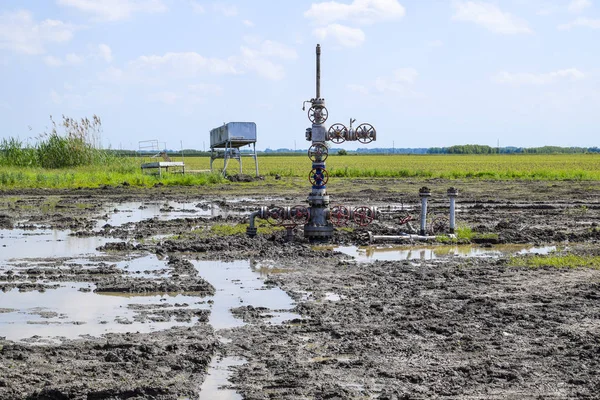 Oil well after repair in mud and puddles.