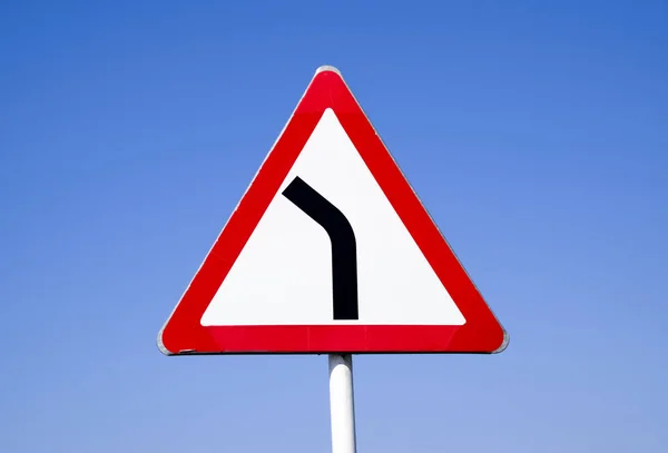 Road sign dangerous turn. Warning sign. — Stock Photo, Image