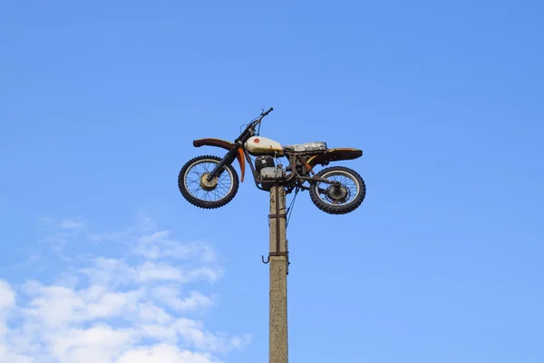 Motorcycle on the pedestal. A light motorbike on a pole, put up as a dummy or a monument