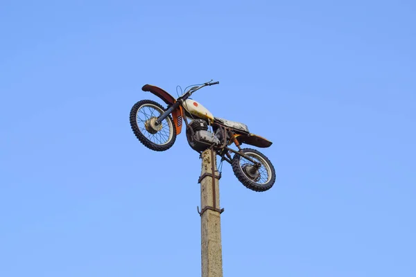 Motorcycle on the pedestal. A light motorbike on a pole, put up as a dummy or a monument