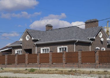Asfalt shingle. Dekoratif bitüm Zona bir tuğla ev çatısında. Oluklu metal çit yapılmış