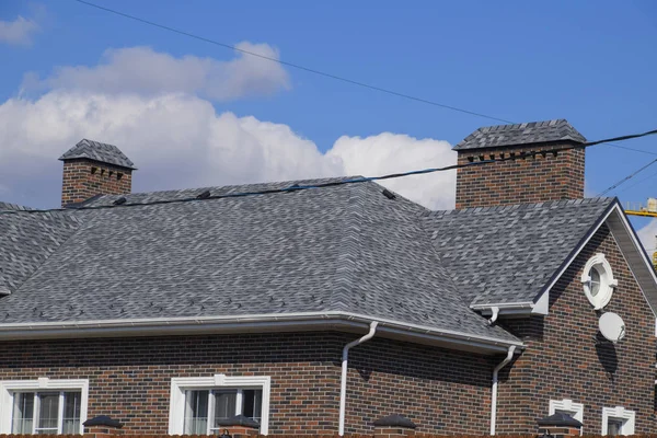 Asphalt shingle. Decorative bitumen shingles on the roof of a brick house