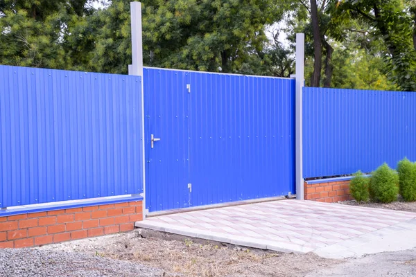 Fence and gate from sheets of blue corrugated metal