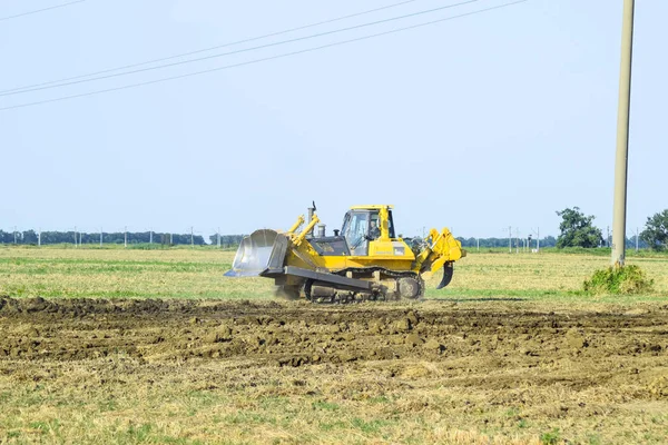 Желтый трактор с прикрепленным гридером делает выравнивание почвы . — стоковое фото