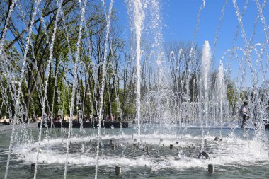Krasnodar, Russia - May 1, 2017: City fountain in the city of Krasnodar. People are walking by the fountain. Water splashes. clipart