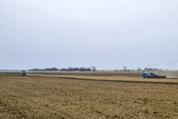 Lush e allentare il terreno sul campo prima della semina. Il trattore aratura un campo con un aratro — Foto Stock