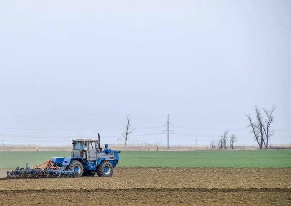 Bujna i spulchniają glebę, na pola przed siewem. Traktor orze pole z pług — Zdjęcie stockowe