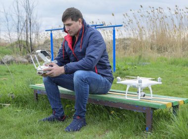 Uzaktan kumanda quadroopter onun elinde olan bir adam oturuyor 