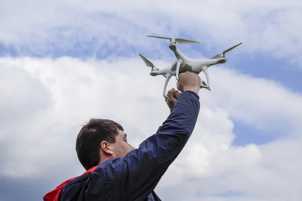 A man with a quadrocopter in his arms raised to the sky. A white