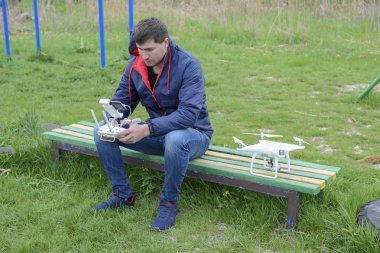 Uzaktan kumanda quadroopter onun elinde olan bir adam oturuyor